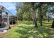 Discover a vast backyard with mature trees, partially viewed through a screened pool area at 14181 Cornewall Ln, Spring Hill, FL 34609