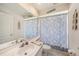 Bright bathroom featuring a seashell-themed shower curtain and white tiled floor at 14181 Cornewall Ln, Spring Hill, FL 34609
