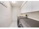 Laundry room with modern front-load washer and dryer, white cabinets, and white tile floor at 14181 Cornewall Ln, Spring Hill, FL 34609