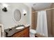 Classic bathroom with an oval mirror, dark vanity and shower with tile surround and a shower curtain at 14341 Passage Way, Seminole, FL 33776