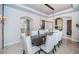 Dining room with a long, dark table surrounded by white upholstered chairs and an ornate light fixture at 14806 Harry Colt Ct, Tampa, FL 33626