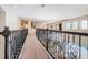 A long, carpeted hallway with dark metal railings overlooks the living area of this bright home at 14806 Harry Colt Ct, Tampa, FL 33626
