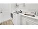 Laundry room featuring a white washer and dryer, sink, cabinets and a door to the exterior at 1528 Highland Park Dr, Clearwater, FL 33756
