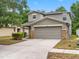 Two-story home featuring a grey exterior, two-car garage, stone accents, driveway and manicured landscaping at 18320 Snowdonia Dr, Land O Lakes, FL 34638