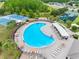 Aerial view of a large community pool with lounge seating and shaded areas near tennis and playgrounds at 18320 Snowdonia Dr, Land O Lakes, FL 34638