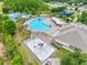 Aerial view of a community pool, splash pad, tennis court, and playground surrounded by lush landscaping at 18320 Snowdonia Dr, Land O Lakes, FL 34638