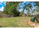 Spacious backyard with green lawn, wooden deck, mature trees and perimeter fence at 2048 Douglas Ave, Dunedin, FL 34698