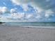 Scenic beach view with calm turquoise water, soft white sand, and a clear blue sky with scattered clouds at 2048 Douglas Ave, Dunedin, FL 34698