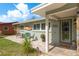 Front view of a well-kept home featuring an inviting porch with seating area and decorative landscaping at 2048 Douglas Ave, Dunedin, FL 34698
