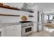 Modern kitchen with stainless steel appliances, herringbone backsplash, and floating wood shelves at 2084 Massachusetts Ne Ave, St Petersburg, FL 33703