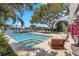 Backyard view of a pool and spa area with patio furniture and a large tree on a sunny day overlooking the water at 2084 Massachusetts Ne Ave, St Petersburg, FL 33703