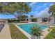 Backyard pool area with an outdoor dining set, lounge chairs and lush, tropical landscaping on a sunny day at 2084 Massachusetts Ne Ave, St Petersburg, FL 33703