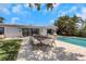 Backyard pool with an outdoor dining table and modern white chairs on a sunny day in a tropical backyard at 2084 Massachusetts Ne Ave, St Petersburg, FL 33703