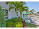 Well-manicured front yard with lush greenery, palm trees, and outdoor seating beneath a turquoise umbrella at 214 Lookout Dr, Apollo Beach, FL 33572