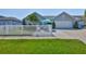 Charming home with a white picket fence, lush lawn, tropical palm, and welcoming outdoor seating area at 214 Lookout Dr, Apollo Beach, FL 33572
