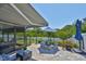 Outdoor patio area with a picnic table, blue umbrella, mature foliage, and comfortable seating beneath an awning at 214 Lookout Dr, Apollo Beach, FL 33572