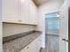 Butler pantry featuring granite countertops, white cabinets, and access to an adjacent room at 3063 Marine Grass Dr, Wimauma, FL 33598