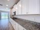 Kitchen showcasing granite countertops, white cabinets, stainless steel appliances, and wood-look flooring at 3063 Marine Grass Dr, Wimauma, FL 33598