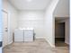 Clean laundry room with washer, dryer, wire shelf, and wood-look tile flooring at 3063 Marine Grass Dr, Wimauma, FL 33598