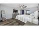 Comfortable bedroom featuring wood floors, a ceiling fan, a TV, and a window with a view of the community at 31775 Sun Kettle Loop Loop, Wesley Chapel, FL 33545