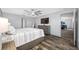 Comfortable bedroom with wood floors, a ceiling fan, a TV on the wall, and a view into the hallway at 31775 Sun Kettle Loop Loop, Wesley Chapel, FL 33545