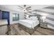 Bright bedroom featuring wood floors, ceiling fan, an accent wall, and a large window overlooking the community at 31775 Sun Kettle Loop Loop, Wesley Chapel, FL 33545