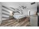 Spacious bedroom with wood floors, ceiling fan, and decorative accent wall with complementary gray and white stripes at 31775 Sun Kettle Loop Loop, Wesley Chapel, FL 33545