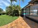 Backyard featuring brick patio, lush landscaping, and a screened-in pool with water views at 3654 Corsair Ct, New Port Richey, FL 34652