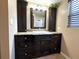 Bathroom vanity featuring dark cabinetry, granite countertops and decorative plant at 3654 Corsair Ct, New Port Richey, FL 34652