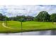 Well-maintained golf green with mature trees, manicured grass, and a tranquil waterway in the background at 36750 Beth Ave, Zephyrhills, FL 33542
