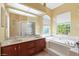 Bathroom featuring double sinks, a soaking tub with garden view, and a glass shower at 4508 Netherwood Dr, Tampa, FL 33624
