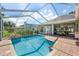 Inviting screened pool with stone waterfall feature, brick patio, and ample seating for relaxation and entertaining at 4508 Netherwood Dr, Tampa, FL 33624