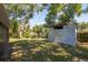 A storage shed is in the backyard, surrounded by a grassy lawn and mature trees at 4706 E Sligh Ave, Tampa, FL 33610