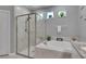 Elegant bathroom featuring a glass-enclosed shower, tub, granite counters, and natural light at 5026 Bromeliad Ave, Wimauma, FL 33598