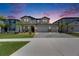 Beautiful home exterior at dusk with manicured lawn and a three-car garage and great curb appeal at 5026 Bromeliad Ave, Wimauma, FL 33598