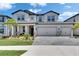 Beautiful two-story home boasts lush landscaping, a three-car garage, and a light gray brick paver driveway at 5026 Bromeliad Ave, Wimauma, FL 33598