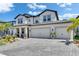 Charming two-story home featuring a three-car garage and brick paver driveway under a blue sky at 5026 Bromeliad Ave, Wimauma, FL 33598
