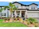 Two-story home featuring manicured landscaping, a covered porch, and a two-car garage at 5026 Bromeliad Ave, Wimauma, FL 33598