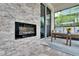An outside fireplace and travertine wall on a covered patio with a seating area and large glass sliding doors at 5026 Bromeliad Ave, Wimauma, FL 33598