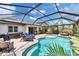 A screened-in pool area featuring lounge chairs, hot tub, a dining table and an outdoor bed at 5026 Bromeliad Ave, Wimauma, FL 33598