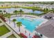 Aerial view of a stunning community pool with lounge chairs, palm trees, and lush landscaping near lake at 5410 Amaryllis Garden St, Apollo Beach, FL 33572