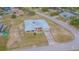 Aerial view of a single-story home on a corner lot, featuring a metal roof, chain link fence, and spacious yard at 5432 Queen Ave, Spring Hill, FL 34609