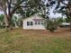 A cozy white house with black shutters and a metal roof and mature trees at 5535 Peach Ave, Seffner, FL 33584