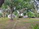 Lush front yard with mature trees, a charming swing, and a view of the home at 5535 Peach Ave, Seffner, FL 33584