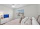 Cozy bedroom with light-colored bedding, window, and a dresser with a television at 8181 Eagles Park N Dr, St Petersburg, FL 33709