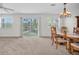 A carpeted dining room with a window and sliding glass doors revealing a beautiful outdoor view at 8181 Eagles Park N Dr, St Petersburg, FL 33709