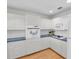 Well lit kitchen with white cabinets, tile backsplash, dark countertops, and wood flooring at 8181 Eagles Park N Dr, St Petersburg, FL 33709