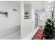 Hallway to a modern bathroom with an enclosed shower and wall-mounted shelves and fixtures at 1014 Sylvia Ln, Tampa, FL 33613