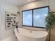 Bright bathroom featuring a modern soaking tub under a large window, accented by tasteful decor at 1014 Sylvia Ln, Tampa, FL 33613