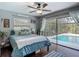 Cozy bedroom featuring a view of the pool, soft blue bedding, and ample natural light at 1014 Sylvia Ln, Tampa, FL 33613